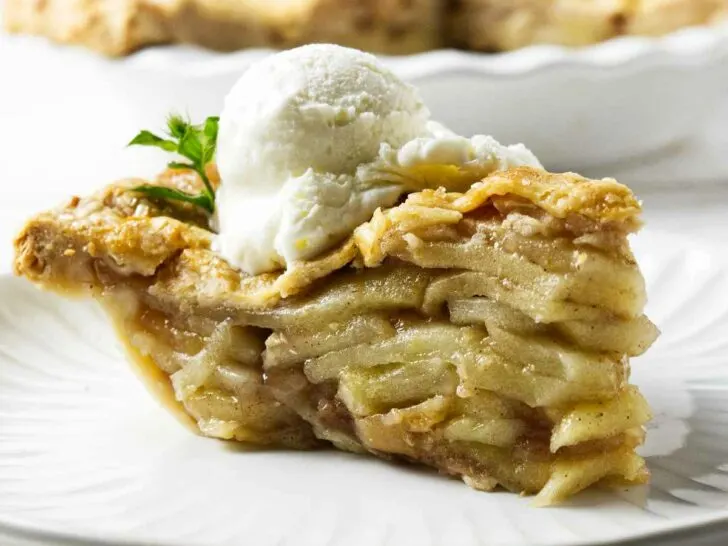 A slice of deep-dish apple pie with a scoop of ice cream.