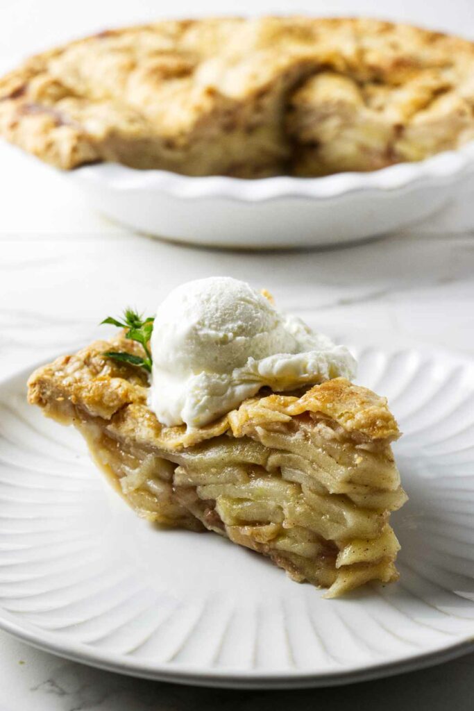 A tall slice of apple pie baked in a deep dish.