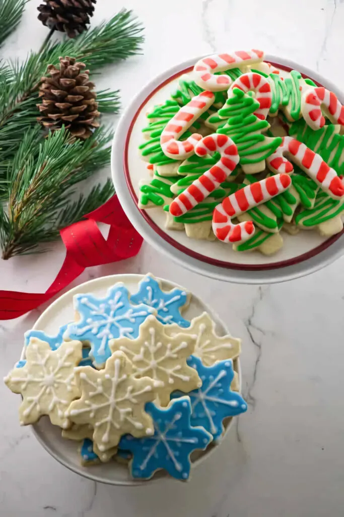 Two platters of cutout sugar cookies decorated for Christmas.