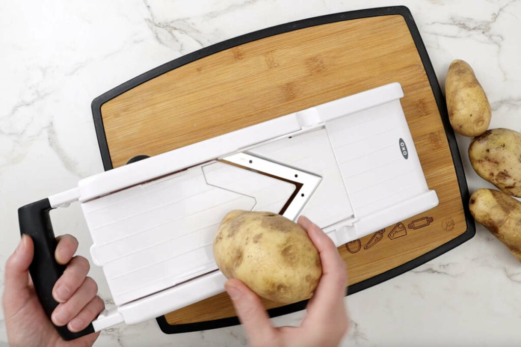 Slicing potatoes with a mandoline slicer.