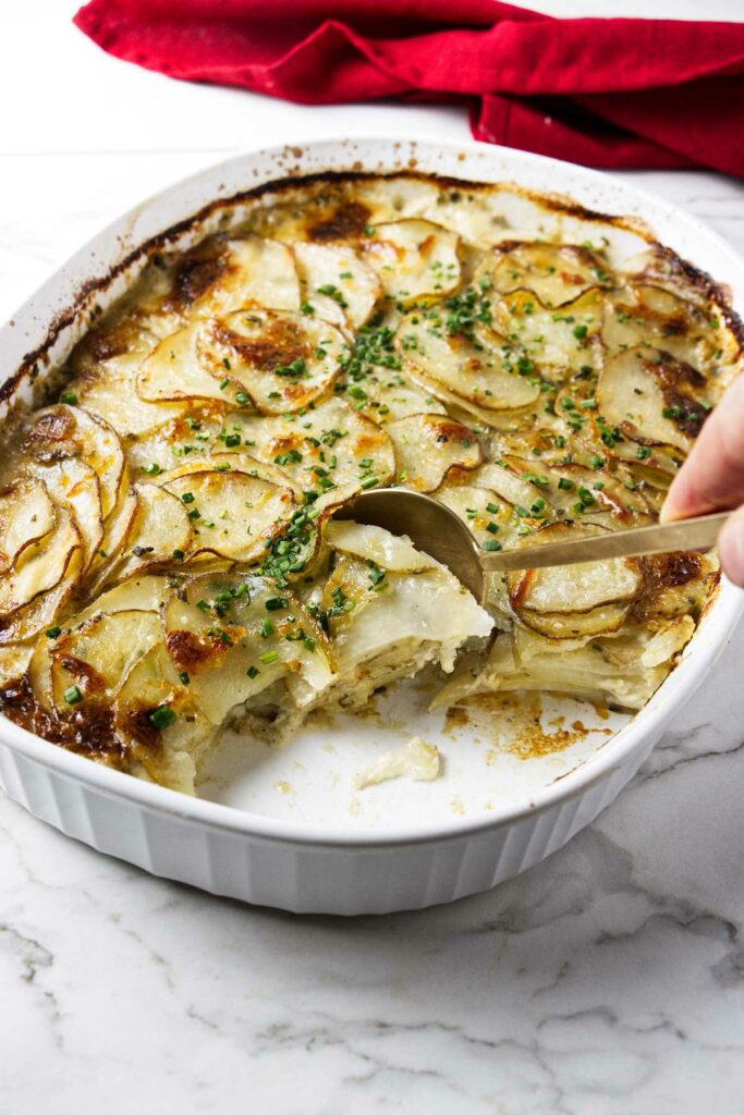 A dish of rosemary potato gratin with a spoon.