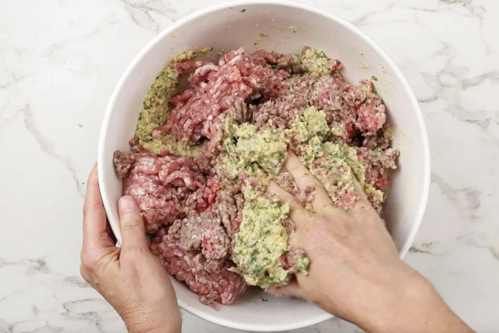 Mixing ground beef and pork with breadcrumbs and seasonings.