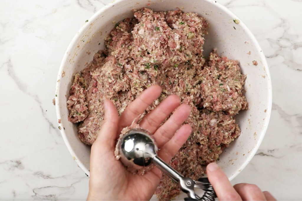 Shaping ground meat mixture into small balls.