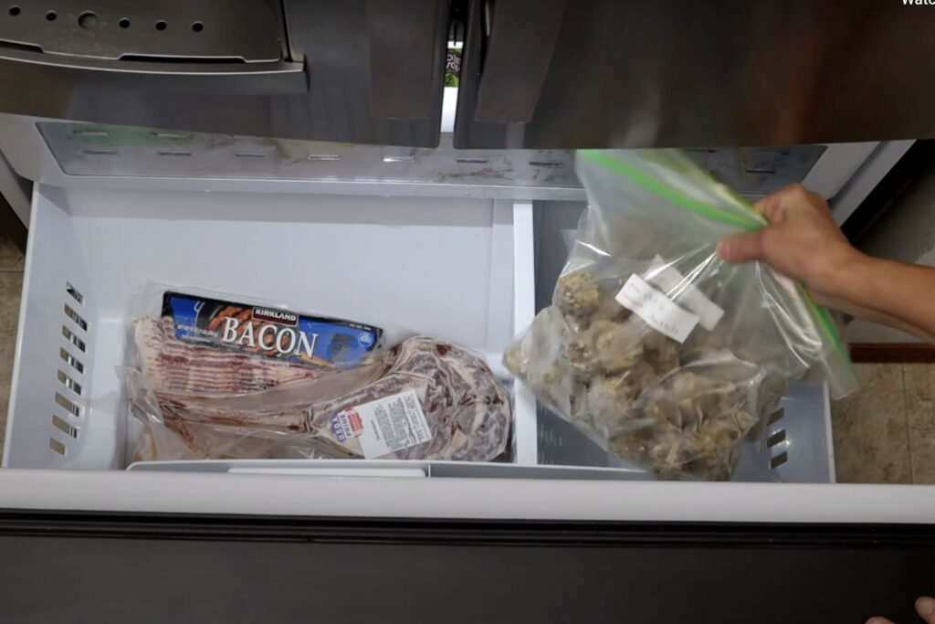 Placing bags of frozen meatballs in the freezer. 