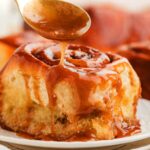 Drizzling caramel sauce over a sticky cinnamon roll.