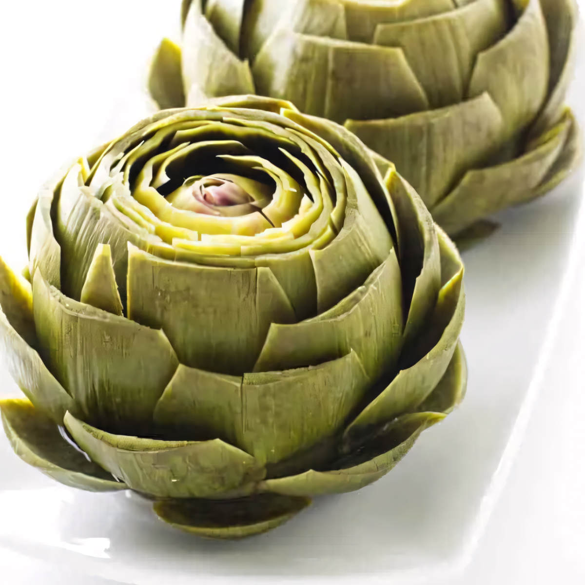 A hot steamed artichoke on a platter.