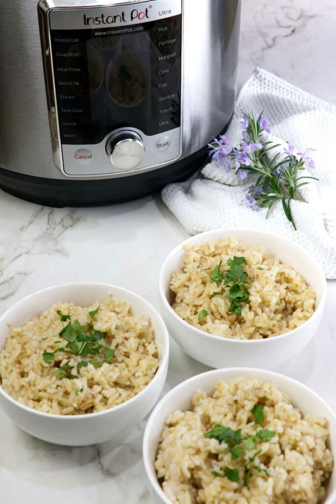 Three bowls of germinated brown rice next to an instant pot.