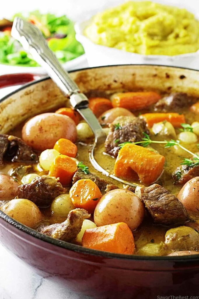 A spoon scooping some lamb stew out of a pot.