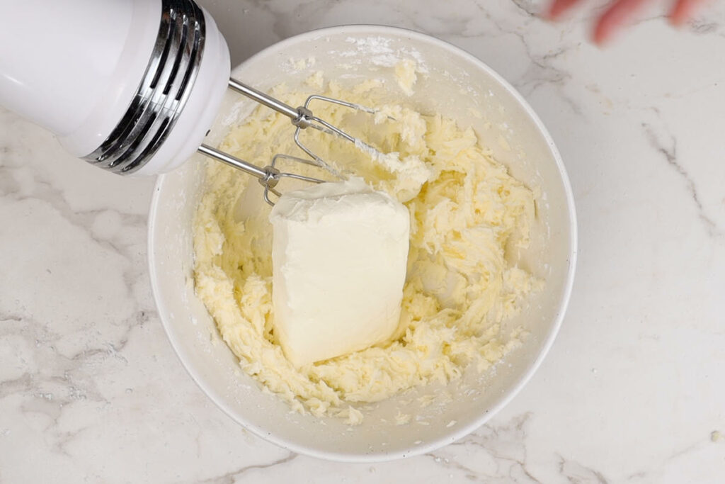 Using and electric mixer to make cream cheese maple frosting.