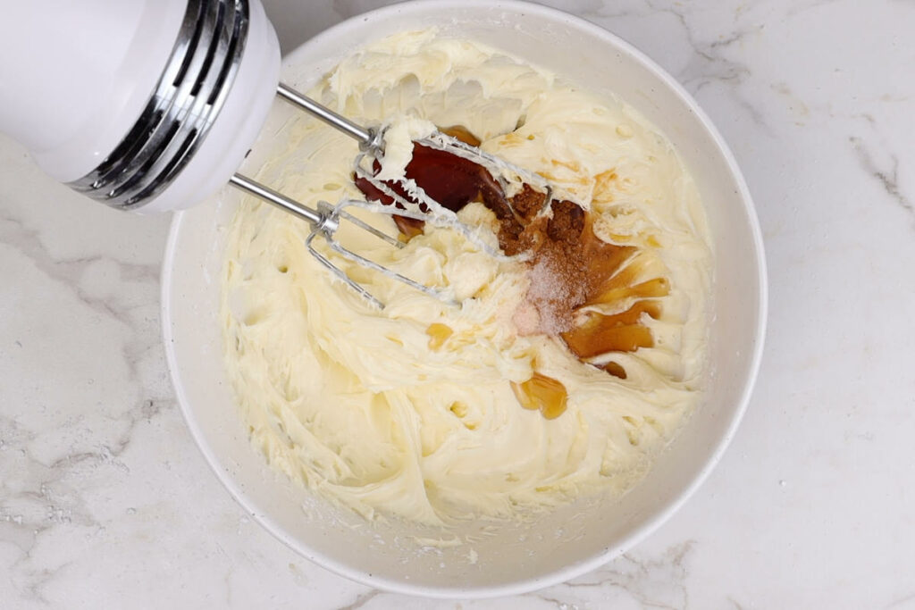 Adding maple syrup to cream cheese frosting.