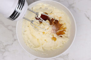Adding maple syrup to cream cheese frosting.