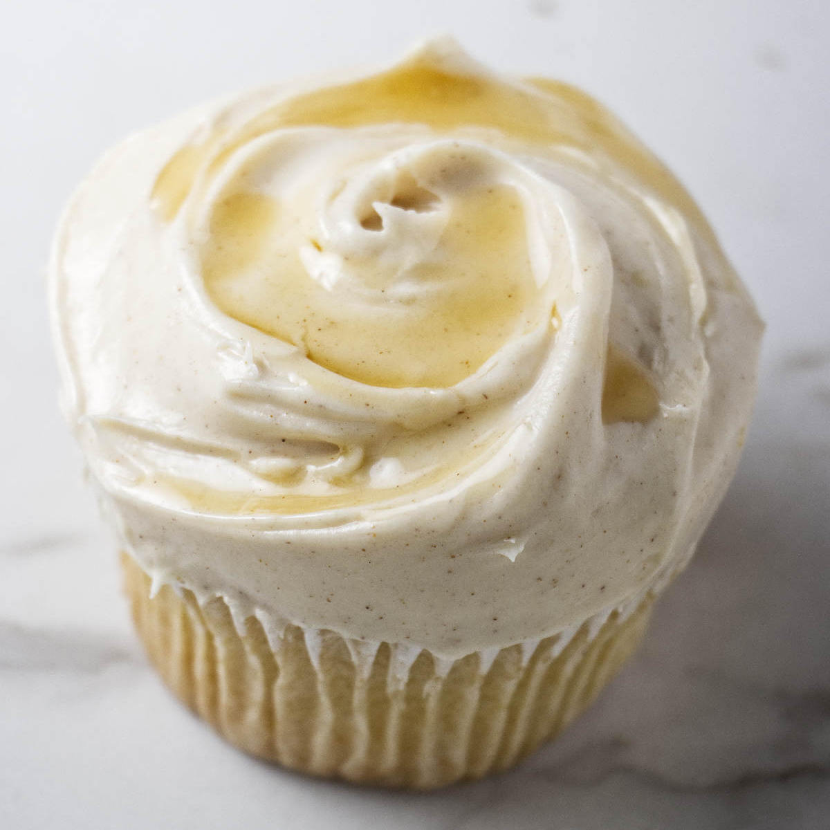 A cupcake topped with maple cream cheese buttercream.