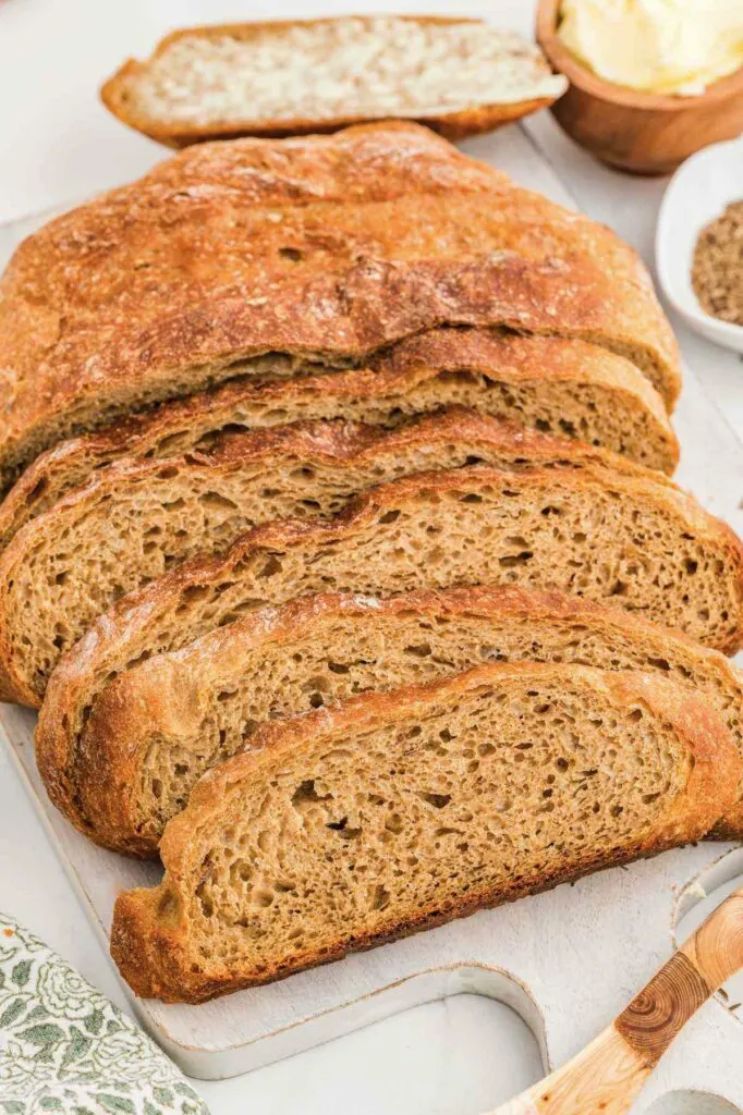 Slices of a simple rye bread recipe next to a dish of caraway seeds.