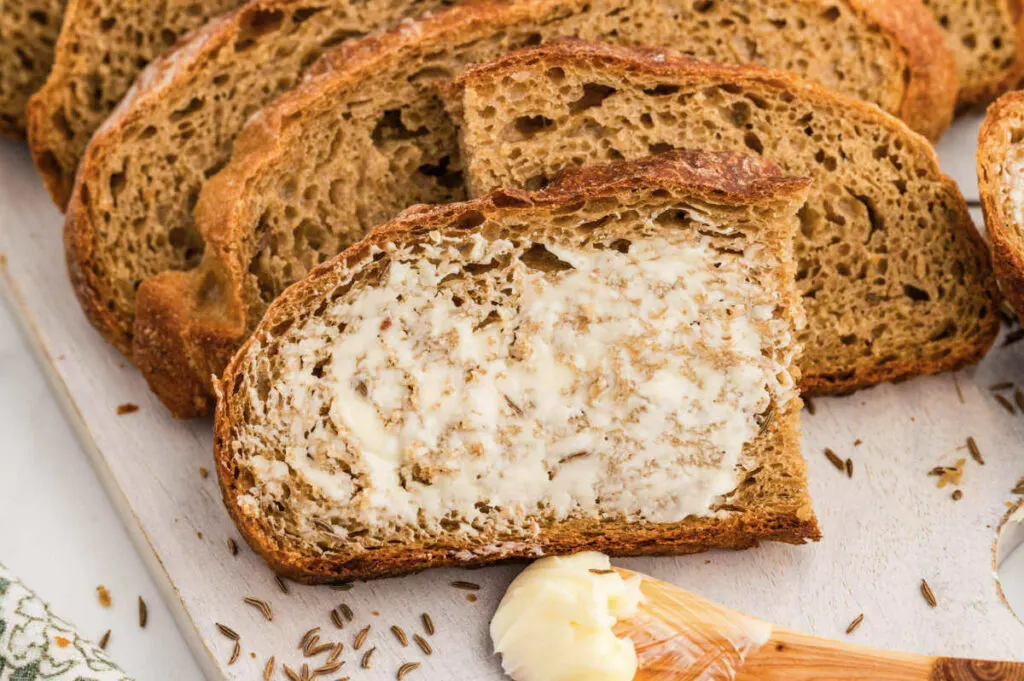 Spreading butter on a slice of rye artisan bread.