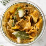 Marinated chanterelles in a jar with herbs and spices.