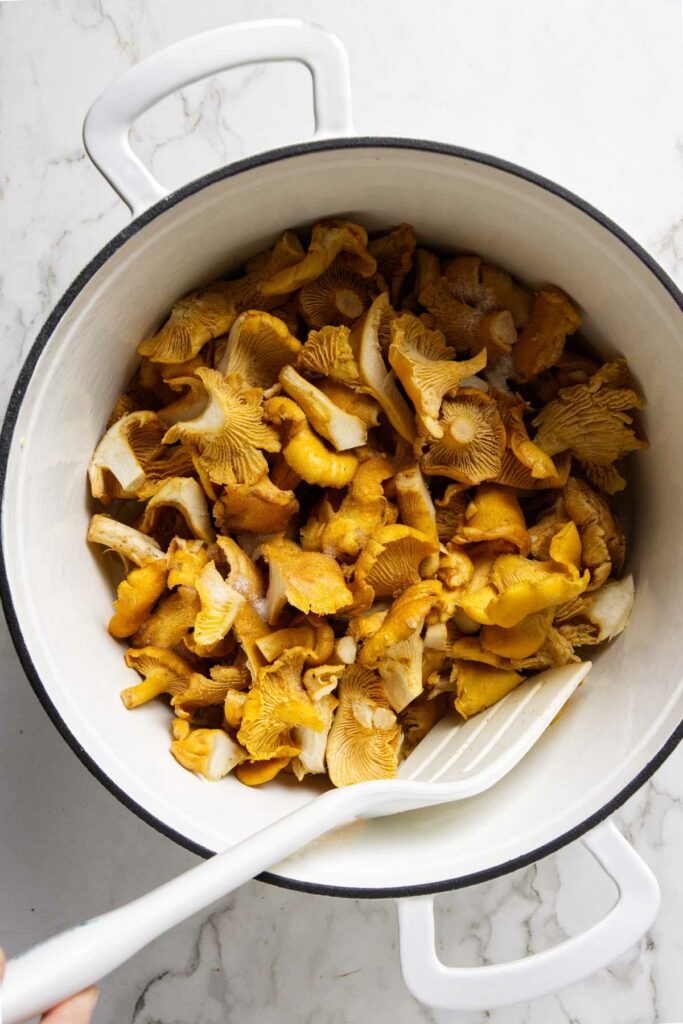 Sautéing chanterelle mushrooms in a large pot.