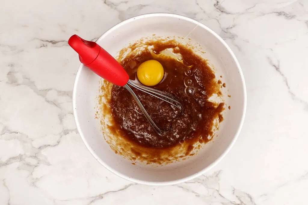 Adding sugar and eggs to sourdough cake batter.