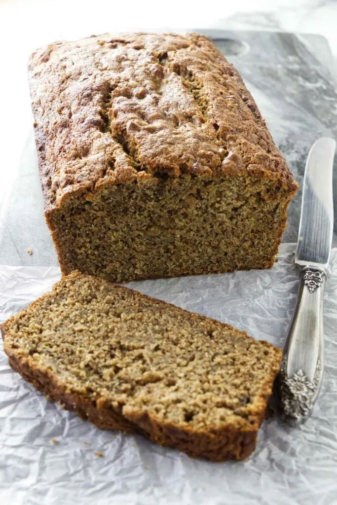 A knife next to a loaf of whole wheat spelt banana bread.