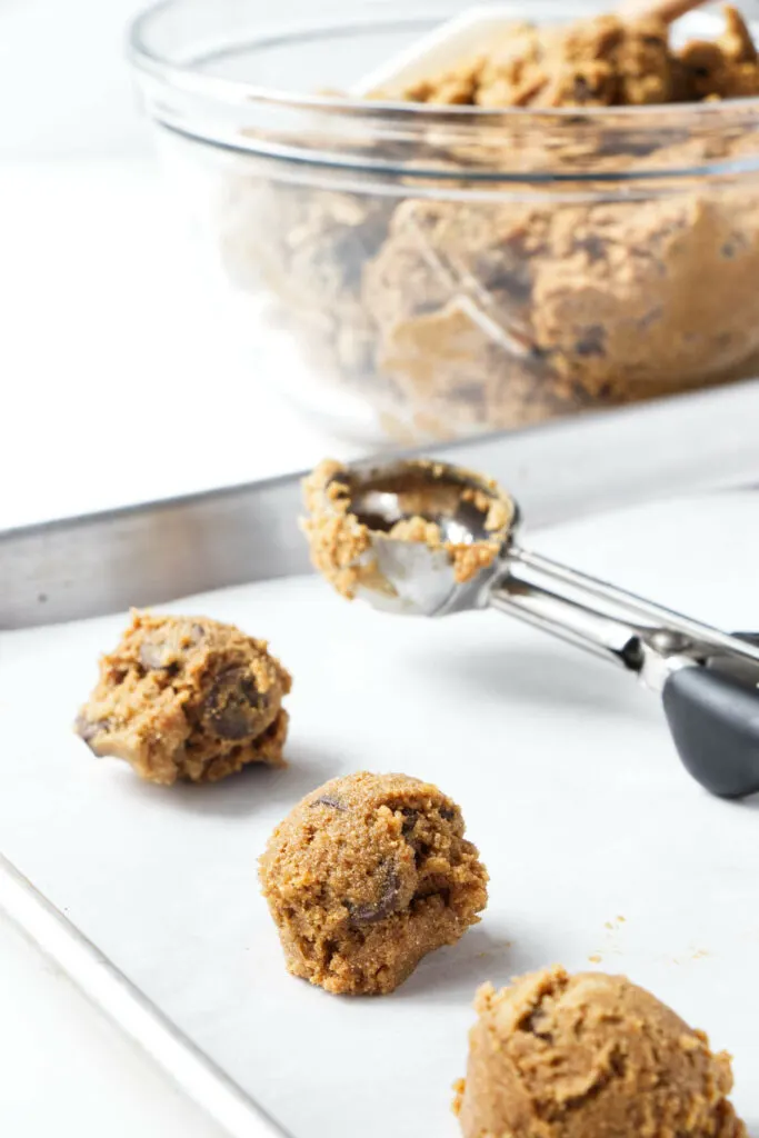 Scooping spelt flour cookie dough onto a baking sheet.