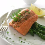 Steamed salmon fillet on a plate with asparagus.