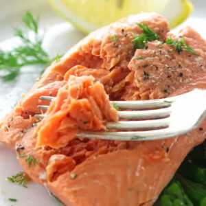 A fork flaking off some salmon cooked in a steamer.