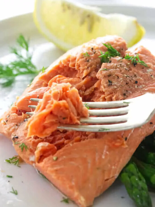 A fork flaking off some salmon cooked in a steamer.