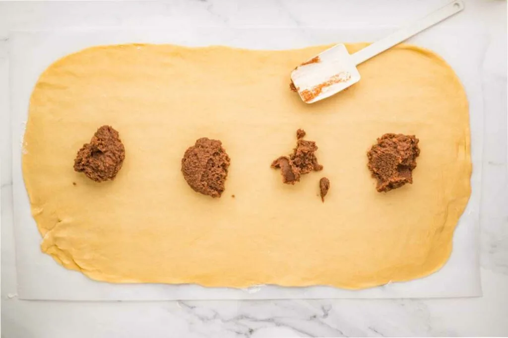 Placing cinnamon butter on dough.