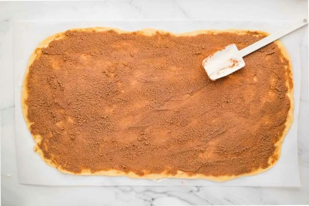 Spreading the cinnamon butter filling onto the dough.