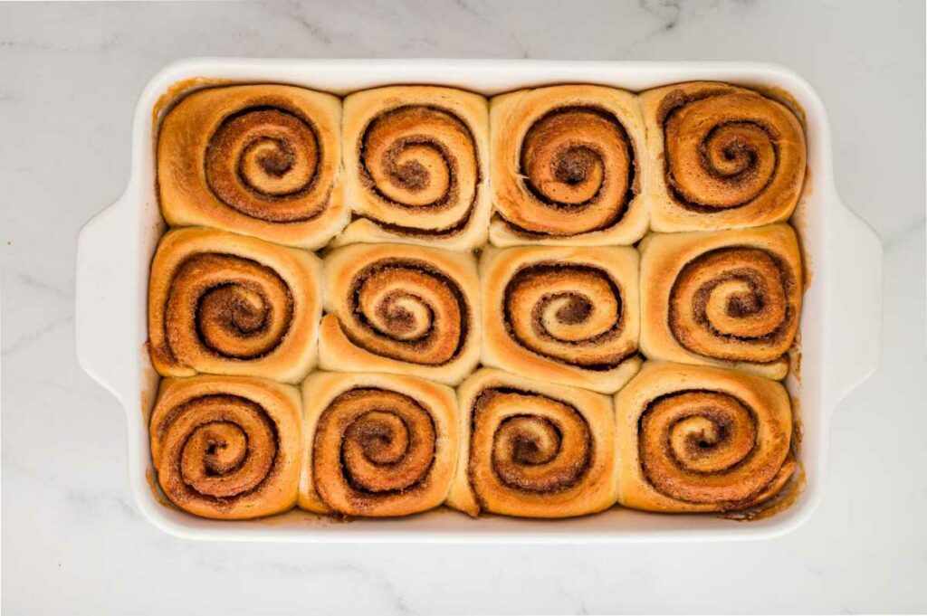 Freshly baked cinnamon rolls in a baking pan, golden brown on top.