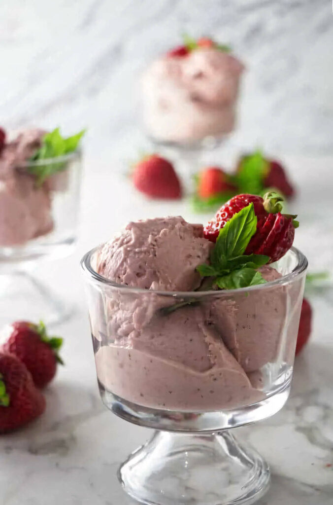 A dish of goat cheese strawberry ice cream with roasted strawberries.