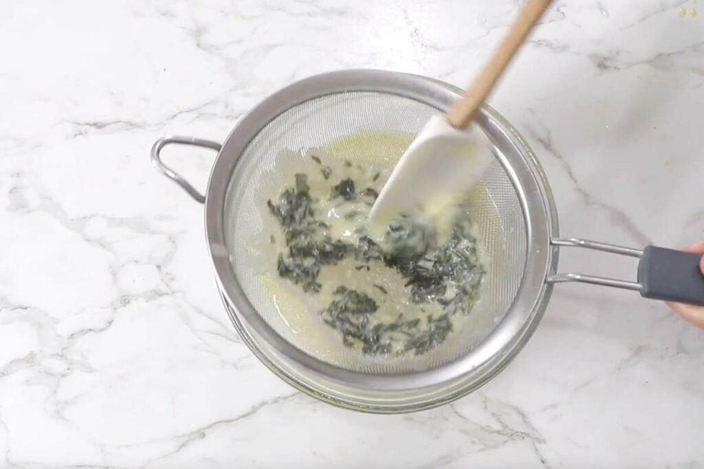 Straining basil from the milk mixture.