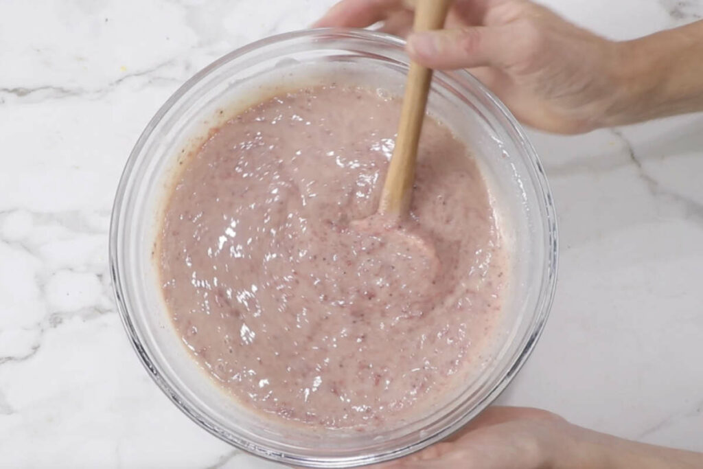 Blending strawberries into the ice cream mixture.