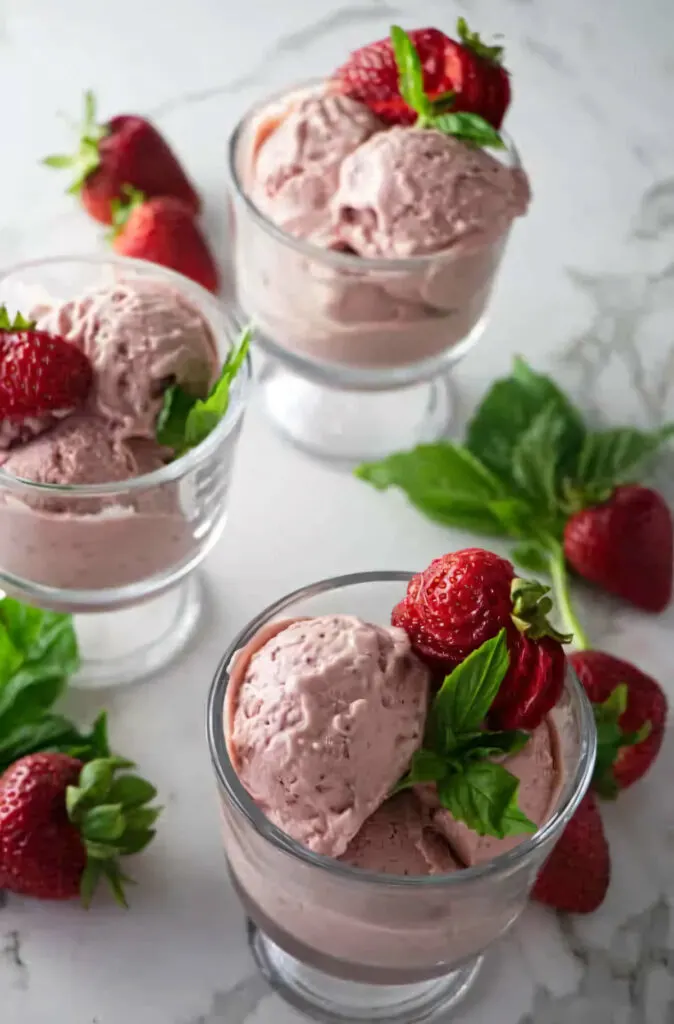 Several glasses filled with strawberry goat cheese ice cream.