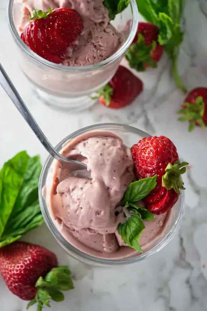 A spoon in a bowl of strawberry and goat cheese ice cream.