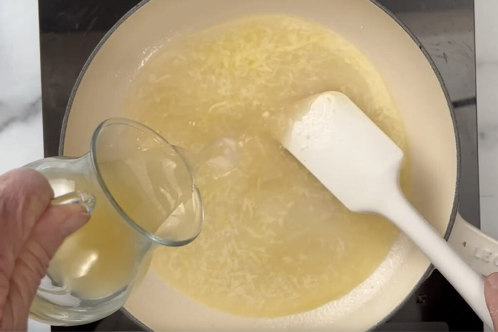 Adding chicken broth and wine to the pan.