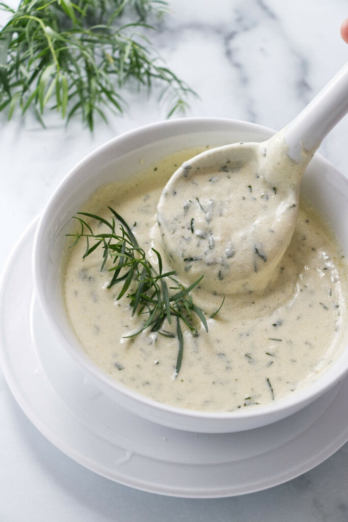 Scooping herbed cream sauce from a bowl.