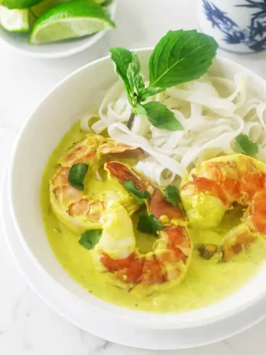 A dish filled with yellow curry prawns and rice noodles.