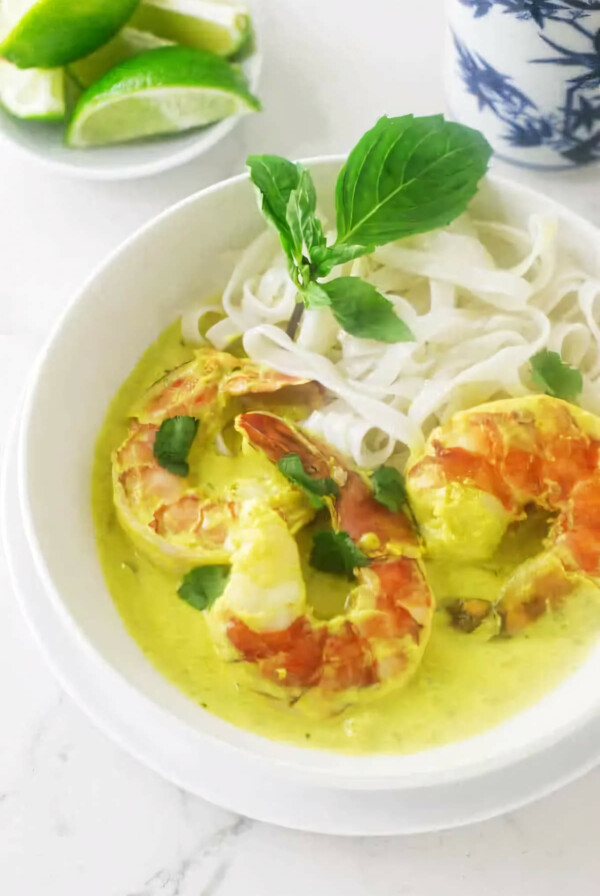 A dish filled with yellow curry prawns and rice noodles.