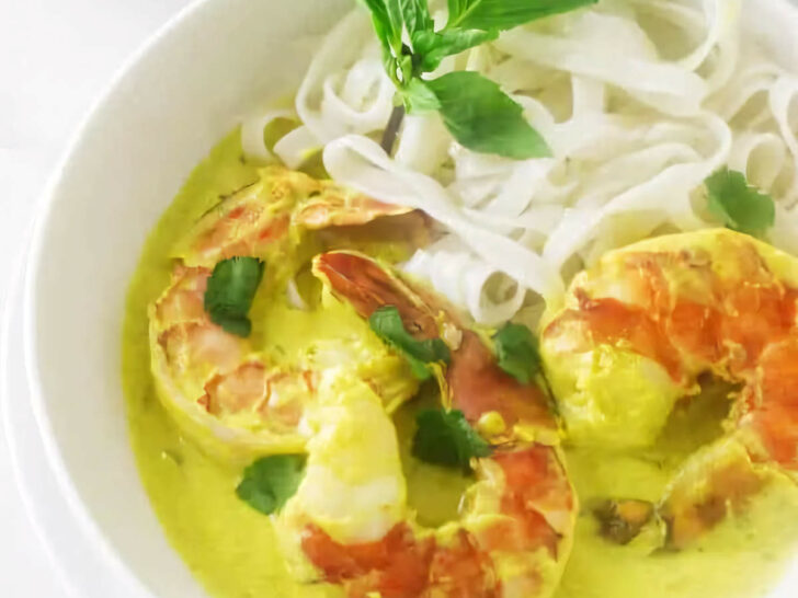 A dish filled with yellow curry prawns and rice noodles.