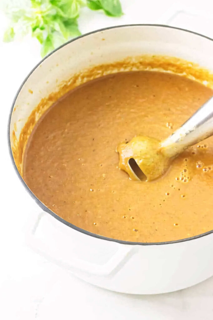 Using an immersion blender to puree soup in a pot.