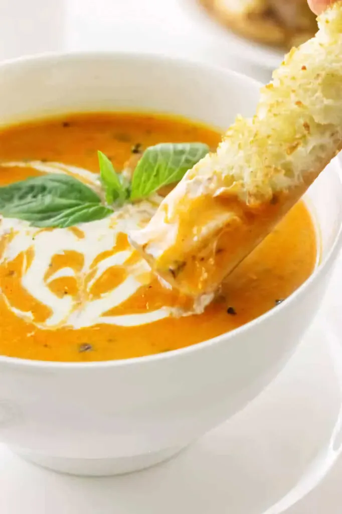 Dipping bread into a bowl of roasted tomato soup.