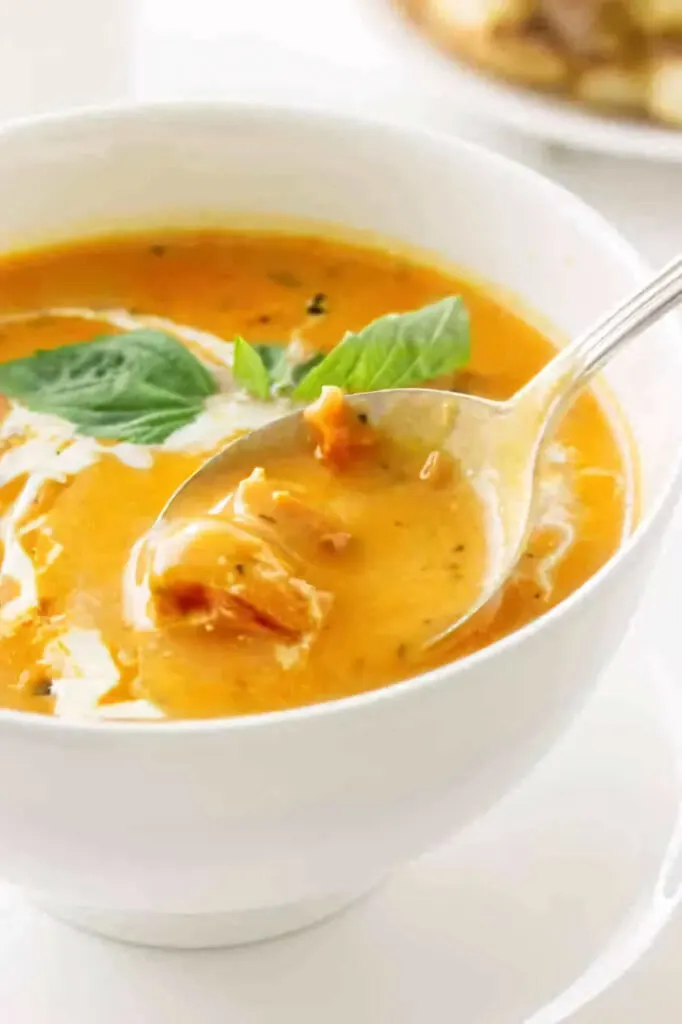 A spoon scooping some tomato soup from a bowl.