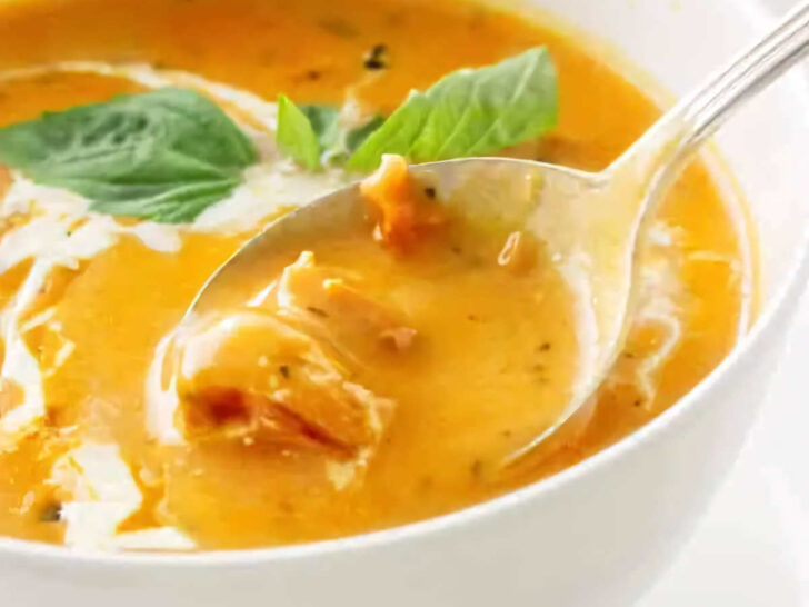 A spoon scooping some tomato soup from a bowl.