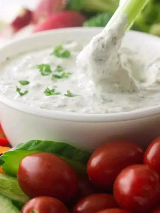 Dipping celery in a bowl of yogurt dip.