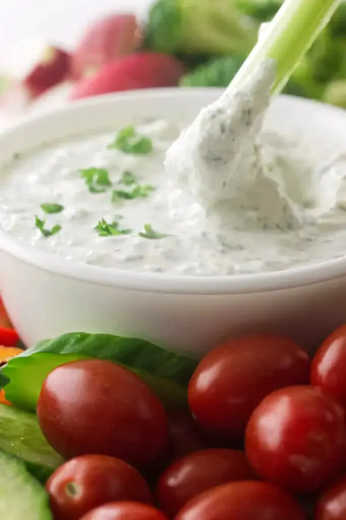 Dipping celery in a bowl of yogurt dip.