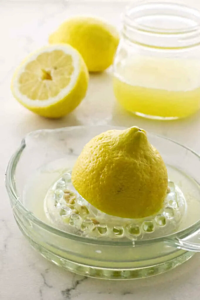 Juicing a lemon on a glass citrus juicer.