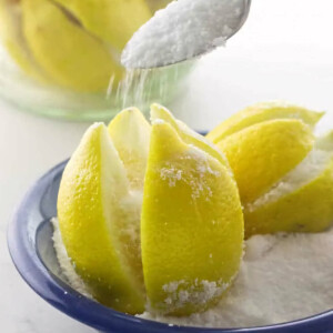 Pouring salt into sliced crevices of a lemon to make preserved lemons.