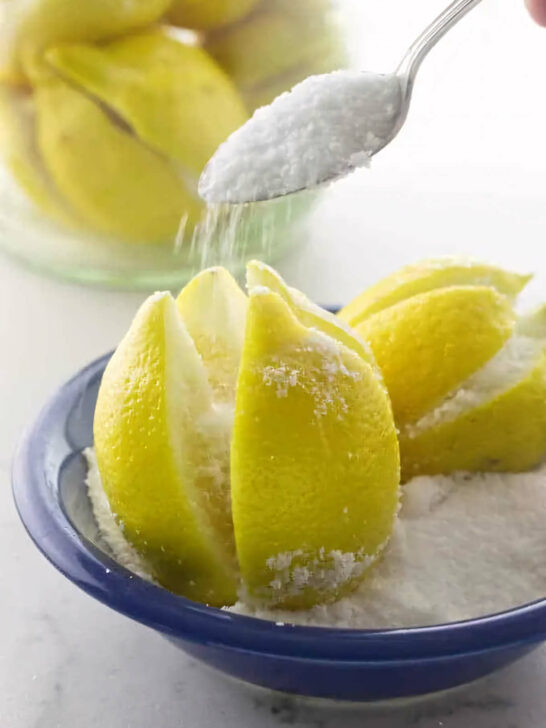 Pouring salt into sliced crevices of a lemon to make preserved lemons.