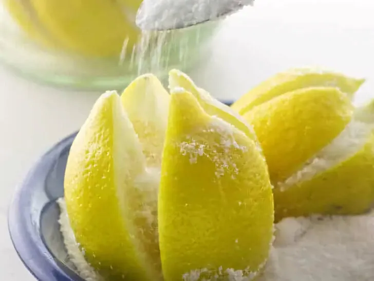 Pouring salt into sliced crevices of a lemon to make preserved lemons.