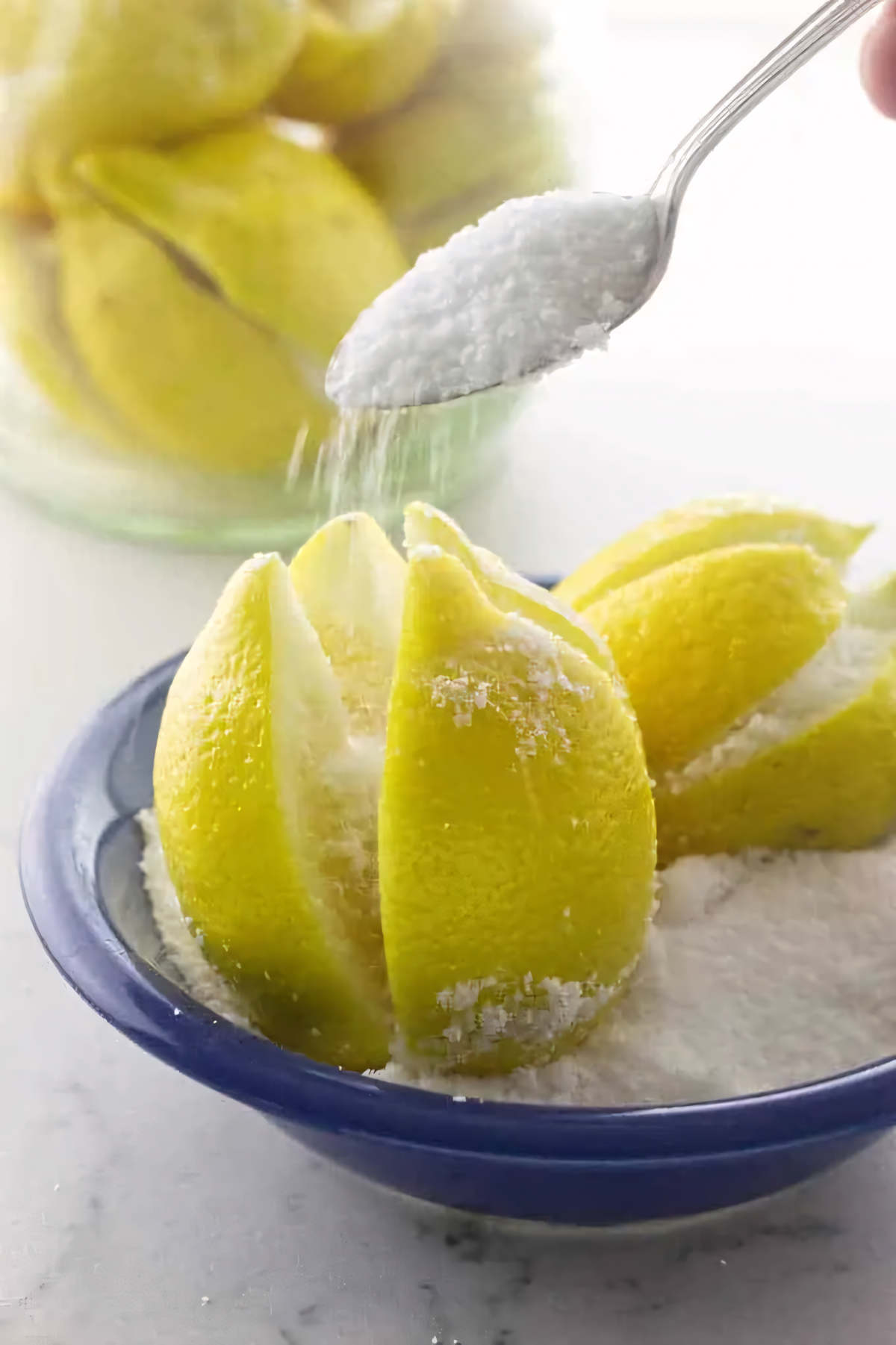 Pouring salt into sliced crevices of a lemon to make preserved lemons.